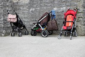 baby strollers near a stone wall