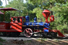 Vintage, colorful engine cab in the Herman Park, near the green plants, in light and hadow