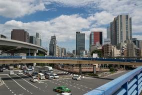 Cityscape of Tokyo, Japan, with the buildings and cars on the road, under the blue sky with white clouds