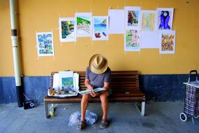 street artist on a bench against a yellow wall