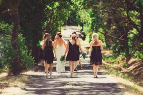 bride with girlfriends on the road among the trees on a sunny day