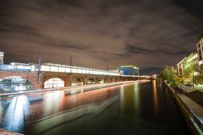 Beautiful landscape with the river, among the buildings with colorful lights, in Berlin, Germany, in the evening
