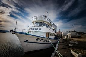 Colorful ship on the water, with the ripple, in the harbor, under the sky with the clouds