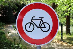 Red, white and black shield with the bike, on the path, among the beautiful, green plants, in sunlight, in Germany