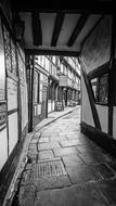 Black and white photo of the beautiful alley, in light, among the buildings in England