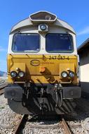 Yellow and white diesel locomotive on the railway, at blue sky on background