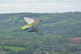 Person, doing hang gliding, above the beautiful, green mountains in Normandy, France