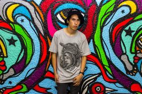 guy in a gray t-shirt on a background of colorful graffiti