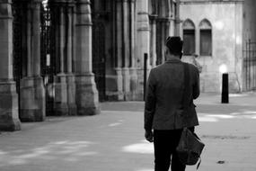 black and white photo of man walking on street