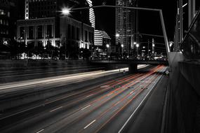 Black and white cityscape of the road, with the colorful lights in motion, at the night