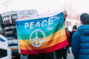 Person with the colorful "PEACE" flag on the rally