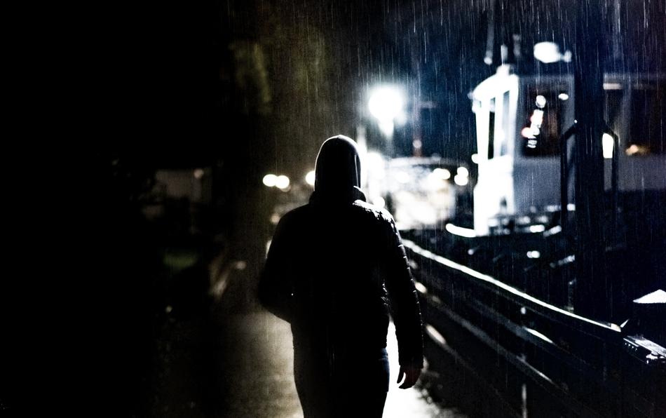 man in hoodie walking on embankment at night