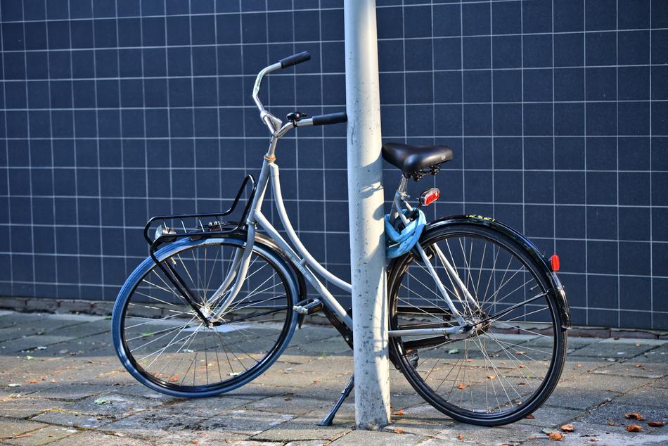 Colorful bike is parked at the grey pillar near the fence