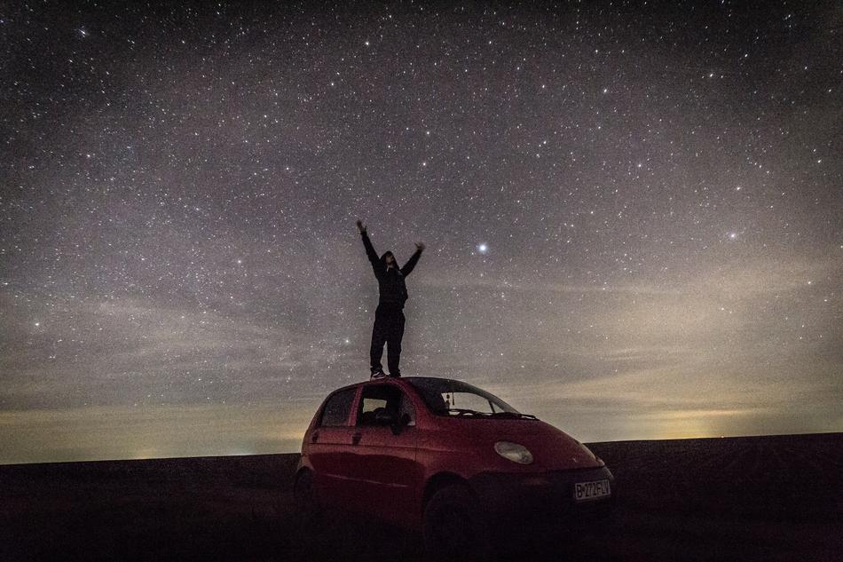 boy on the roof of a car under the starry sky