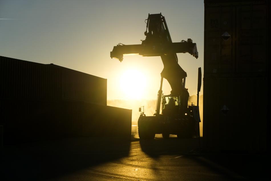 Silhouette of the crane near the containers at background with sunrise