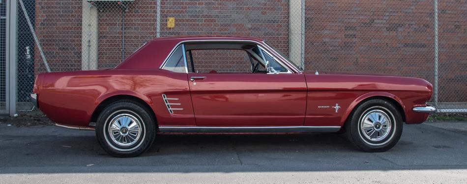 photo of a red ford mustang on a brick wall background