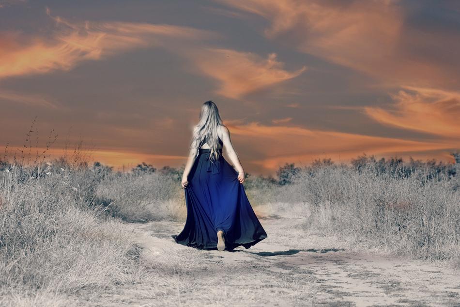blonde in a blue dress in a mystical landscape at dusk