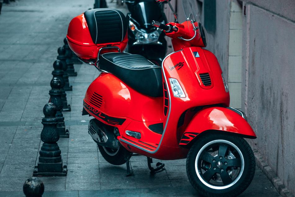 Shiny, red and black motorcycle scooter on the street, near the building in Ä°stanbul, Turkey