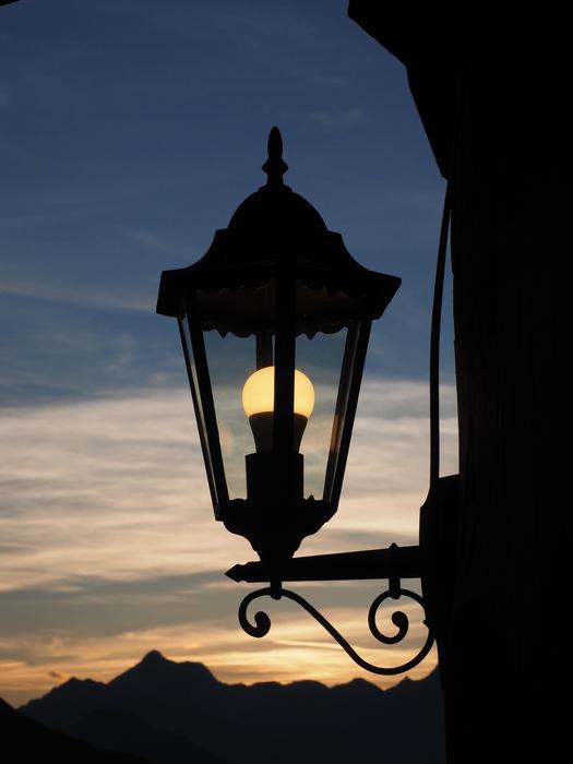 Silhouette of a lantern, with the light, at background with the mountains and beautiful sunset, in Jaufenpass, Italy