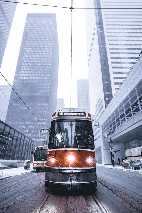 Colorful and beautiful tram, among the snowy city with the buildings, in winter