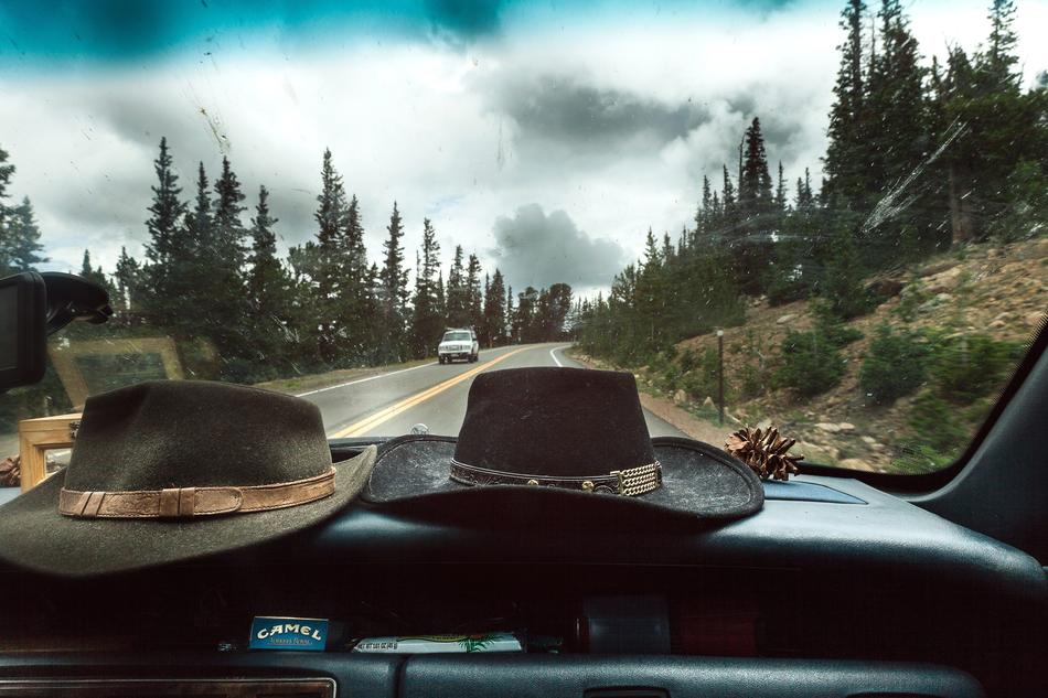 Cowboy hat on the dashboard of the car, on the road, among the colorful and beautiful plants
