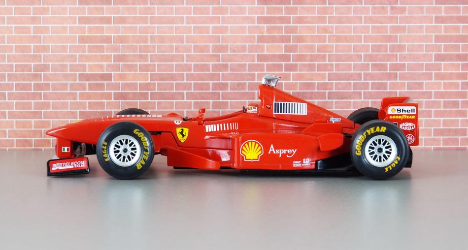 Side view of the red, yellow, black and white Ferrari F300 Formula 1 car of Michael Schumacher