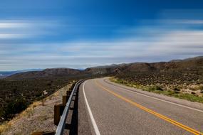 Beautiful and colorful landscape of the highway, with the fence, on the mountains, in California, USA, at blue sky with clouds