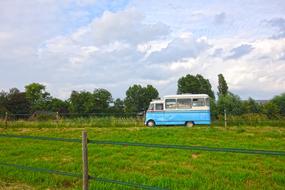 White and blue bus among the green field near the green trees on the beautiful landscape in Amstelveen, Netherland