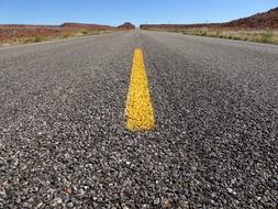 Low angle shot of the beautiful landscape with the highway with yellow lines, among the colorful fields in Utah, USA