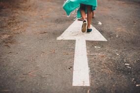 girl on a white arrow on a country road