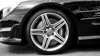 Black and white photo with the side view of the beautiful, shiny car, with the alloy wheel