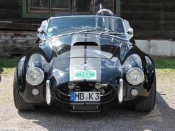 Beautiful, shiny, black car with the stripes, in light, near the building, in shadow