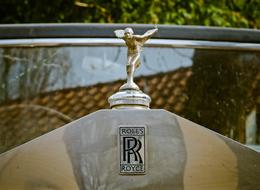 Beautiful, shiny figure of the retro Rolls Royce car, near the plants