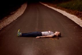 Girl, laying among the road at twilight