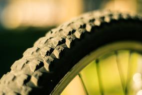 Close-up of the bike knobbly tire, in light, at blurred background