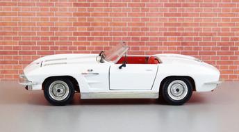 Side view of the beautiful, white Corvette Stingray car, near the brick wall