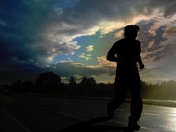 silhouette of a runner on the road at dusk