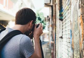 Guy, taking photo of the street, in light, with the colorful graffities