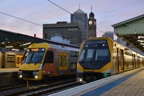 Colorful trains on the train station, near the buildings in Sydney, Australia, at colorful sunset