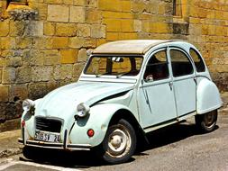 Shiny, old, vintage car, on the road, near the stone wall