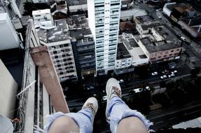 Person in ripped jeans, sitting on the top of the building