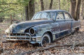 Old, antique car, on the colorful leaves, among the green trees