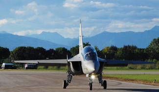 Plane in sunlight, on the lane, among the colorful plants and mountains, under the clouds