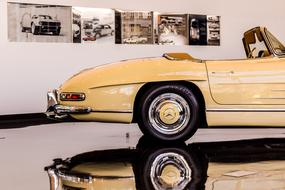 Side view of the beautiful, shiny, cream, vintage car, with the reflection in the floor