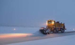 Snow plow with colorful lights, on the beautiful road among the snow, in the winter