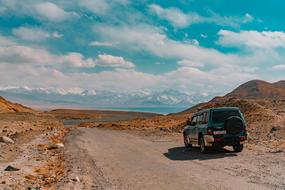 green truck on the road against the background of mountains