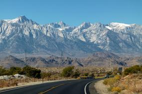 Beautiful landscape of the road, among the colorful plants, near the beautiful, snow capped Sierra Nevada mountains in California, USA