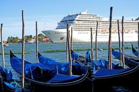 Gondolas and cruise ship in the port of Venice, Italy, in sunlight