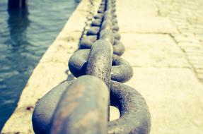 Close-up of the metal anchor chain on the coast of the water, with ripple
