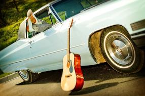 guitar near a vintage car on a sunny day